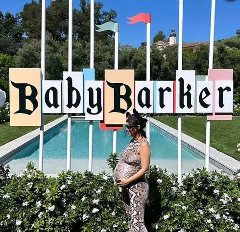 Kourtney Kardashian in front of Baby Barker Disneyland sign
